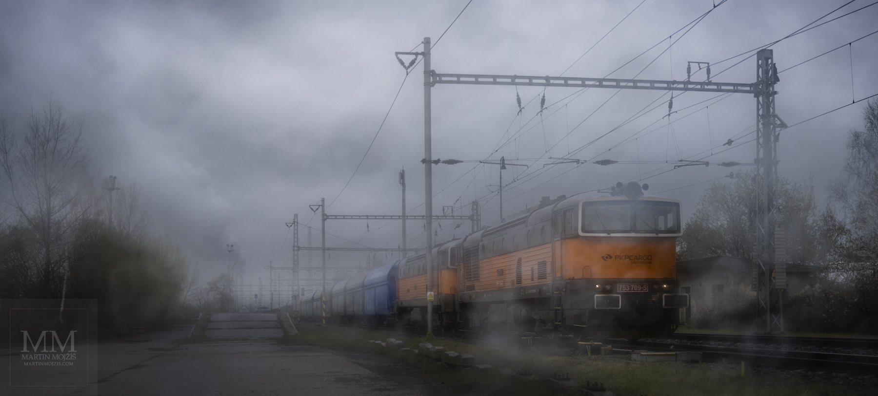 A pair of orange class 753 locomotives, led by 753 709-5, lead a coal freight train.