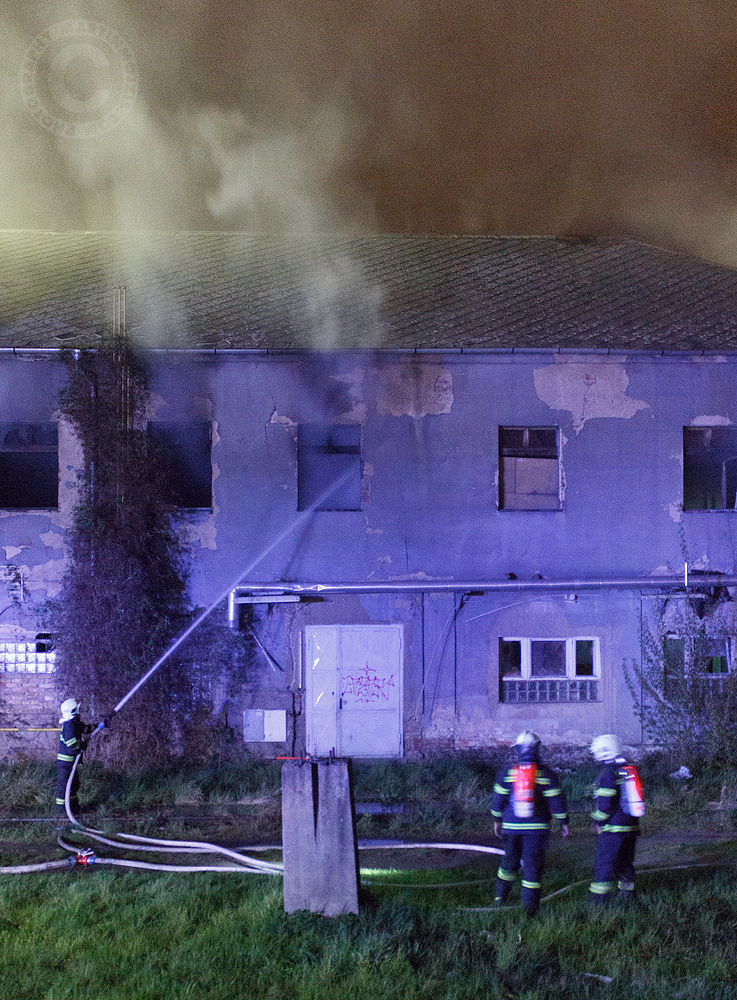 A fireman sprays water through a window into a burning house. Fire at the railway station in Kralupy nad Vltavou.