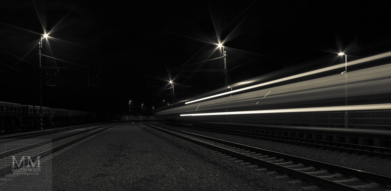 Projíždějící osobní vlak. Nádraží Kařízek v noci.