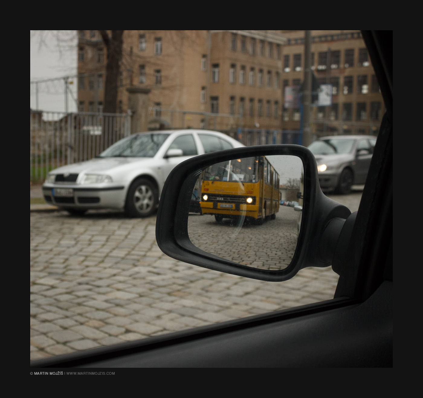A yellow bus Ikarus 260 in a rear view mirror.