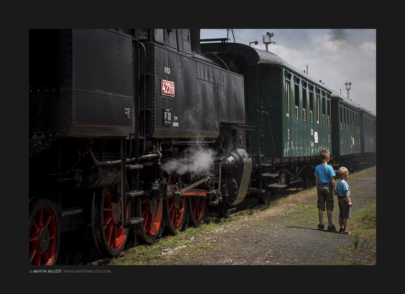 Two little boys stand by a historic steam train. Kolesovka 2017.