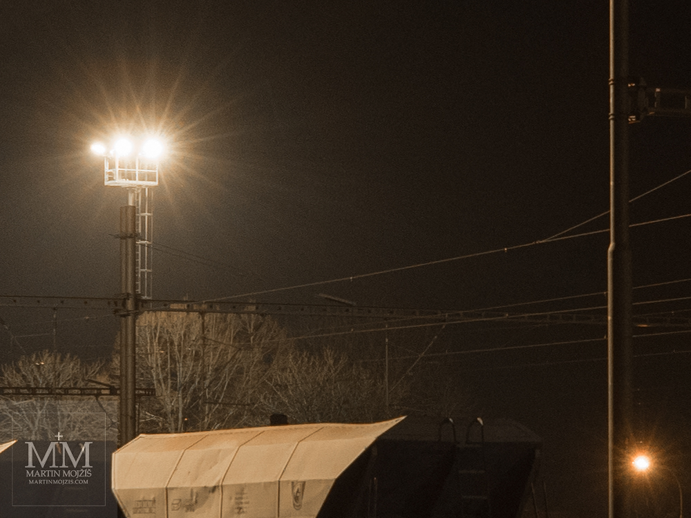 Reflektory osvětlují noční nádraží. Fotografie zhotovená objektivem Olympus M. Zuiko digital ED 25 mm 1:1.2 Pro.