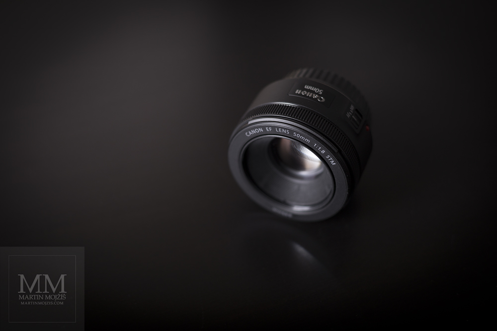 Fotografie objektivu Canon EF 50 mm 1:1.8 STM, pohled shora zepředu, bez clony objektivu.