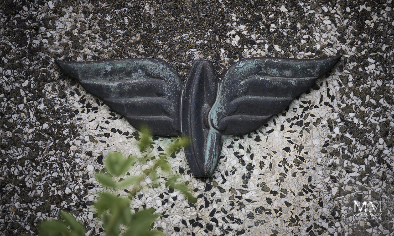 Metal sculpture of a winged railway wheel mounted on a stone. Fine art photograph THE WHEEL, THAT FLIES, photographed by Martin Mojzis.