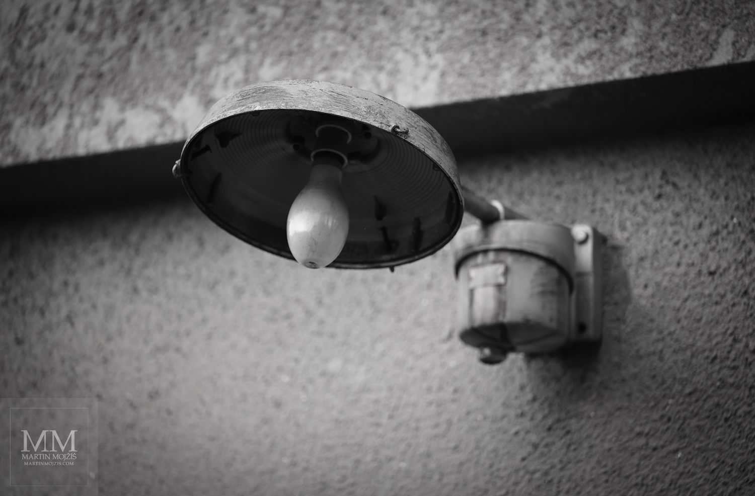 Lampa na stěně. Umělecká černobílá fotografie s názvem U LAMPY. Fotograf Martin Mojžíš.