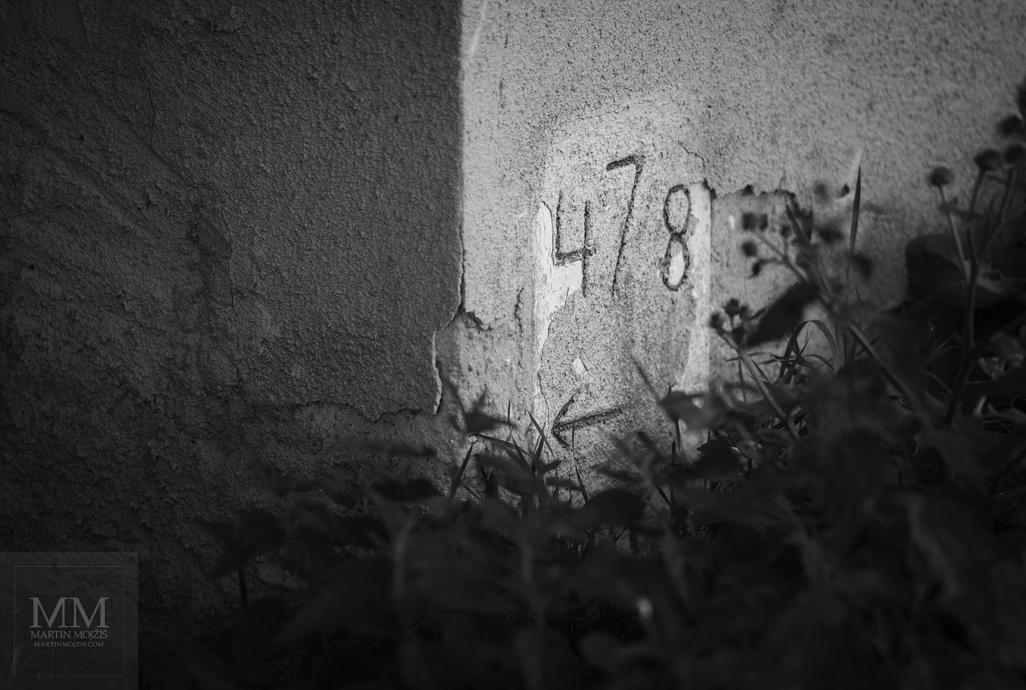 Železniční hektometrovník ve stěně domu. Umělecká černobílá fotografie s názvem VE STĚNĚ II. Fotograf Martin Mojžíš.