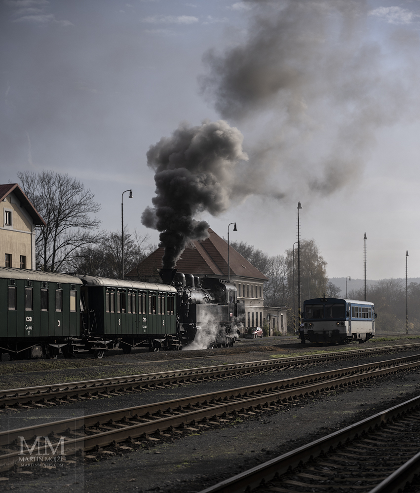 A steam locomotive and a little engine train at a railway station. Fine art photograph AT THE HALF OF AUTUMN, photographed by Martin Mojzis.