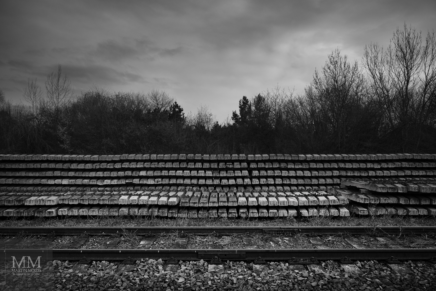 Mnoho železničních pražců vedle kolejí. Umělecká černobílá fotografie s názvem MNOHO PRAŽCŮ. Fotograf Martin Mojžíš.