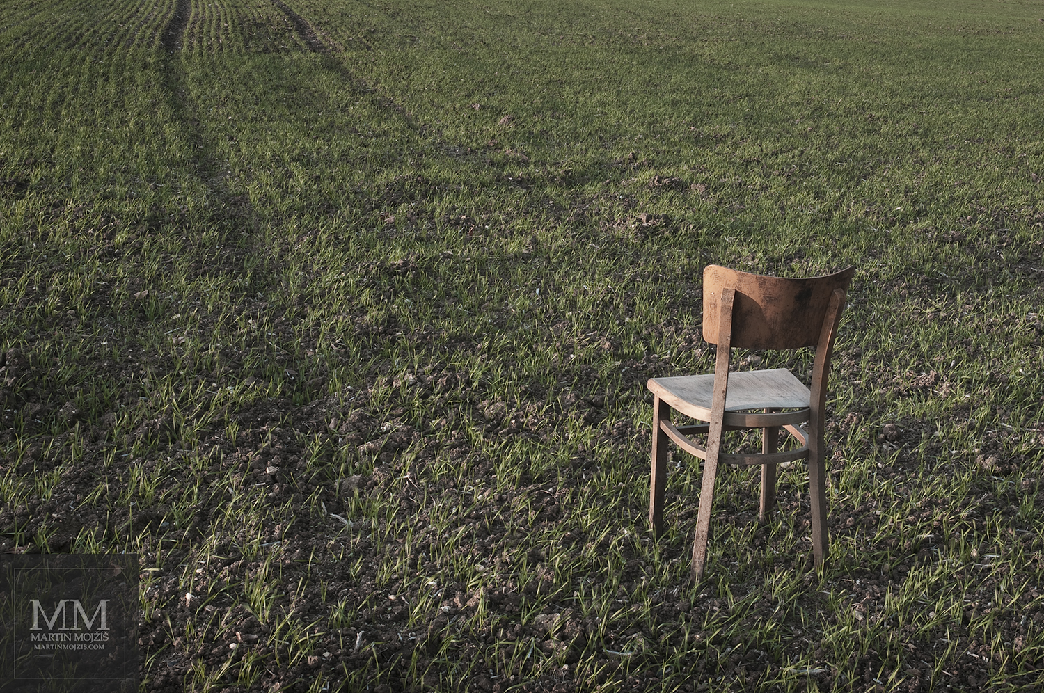 Židle stojící na poli. Umělecká fotografie Martina Mojžíše s názvem ŽIDLE I.
