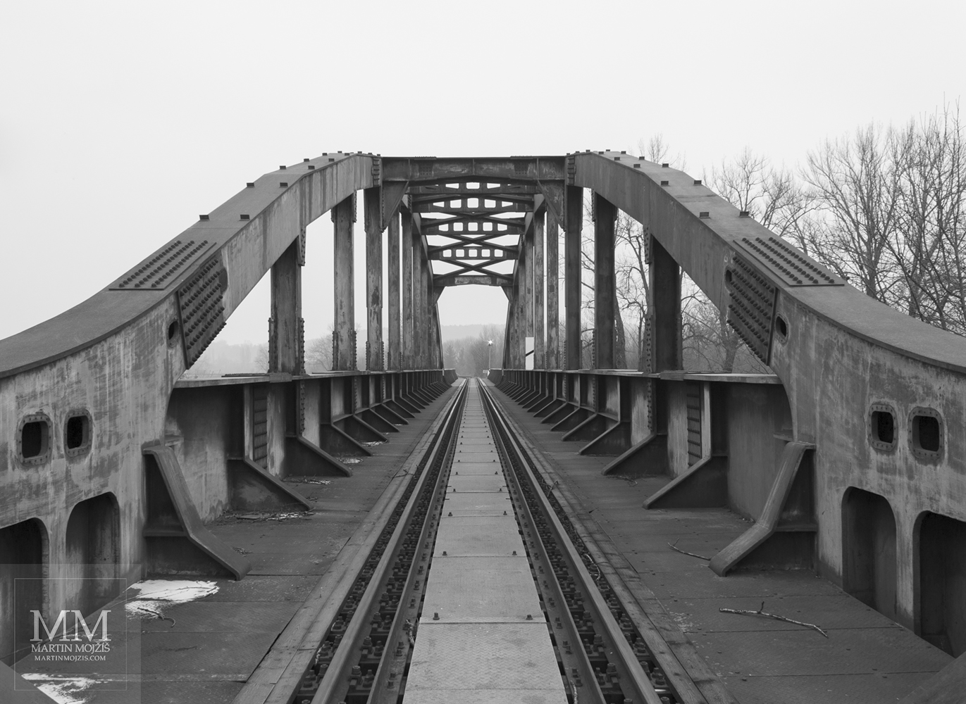 Oblouky konstrukce ocelového železničního mostu. Umělecká černobílá fotografie Martina Mojžíše s názvem K OBZORU.