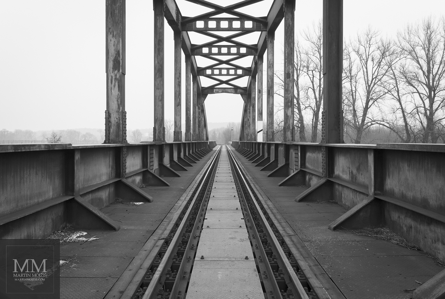 Ocelový železniční most přes řeku. Umělecká černobílá fotografie Martina Mojžíše s názvem NENÍ TO DALEKO.