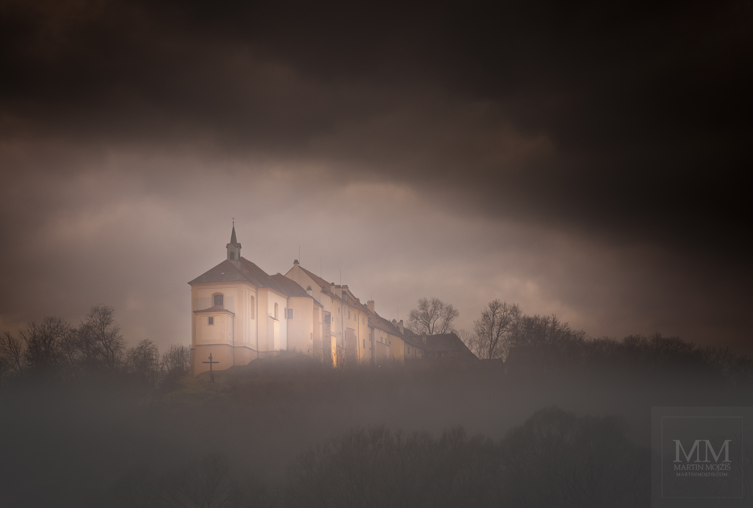 Velkoformátová umělecká fotografie zámku na ostrohu v mlhách.