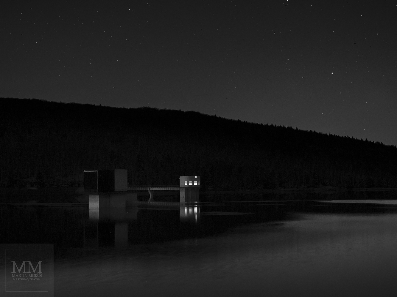 Černobílá umělecká fotografie noční přehrady.