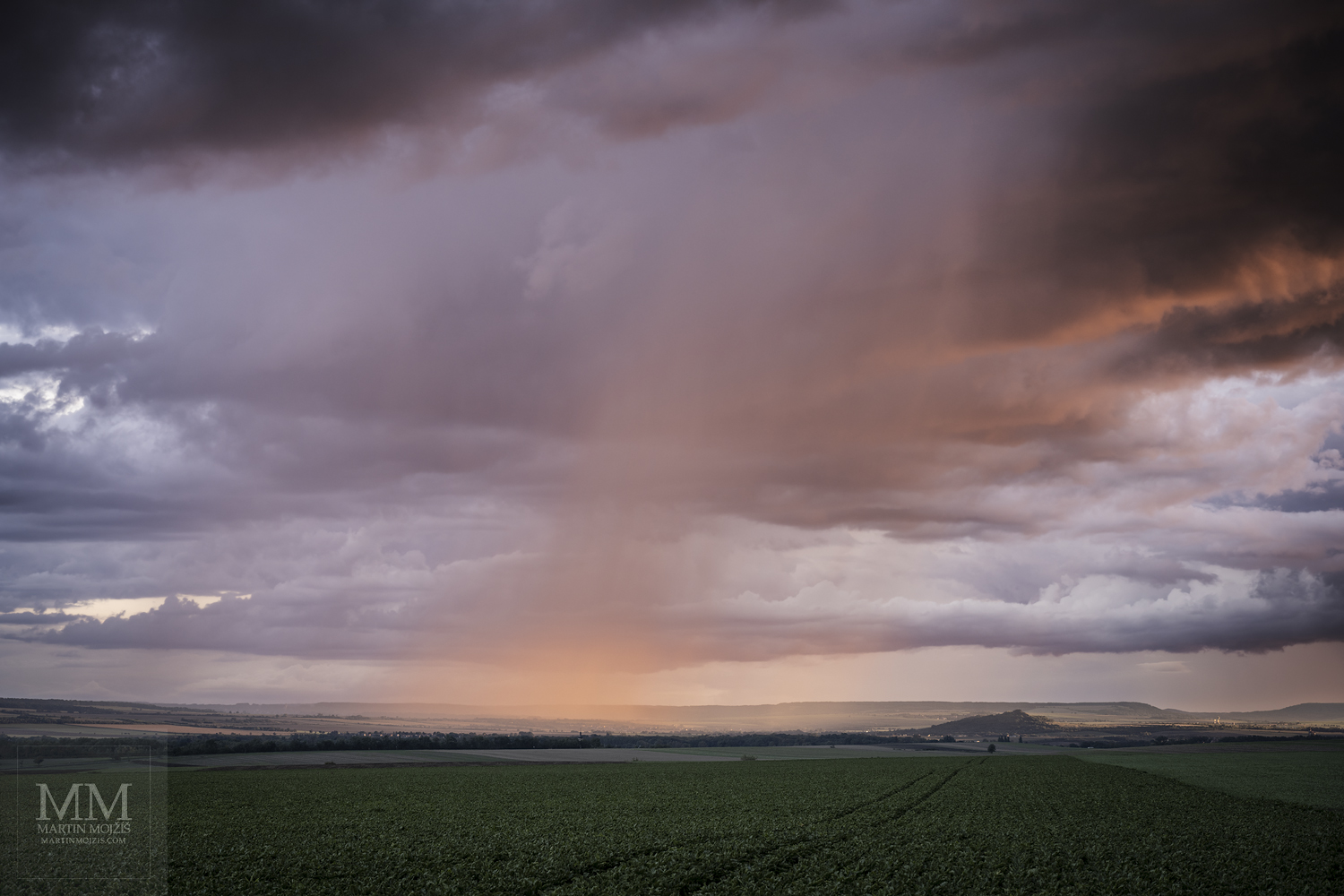 Déšť nad krajinou ve světle zapadajícího Slunce. Umělecká velkoformátová fotografie Podvečerní déšť. Fotograf Martin Mojžíš.