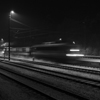 Noční vlak jedoucí po osvětlené zasněžené trati.