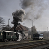 A steam locomotive and a little engine train at a railway station.