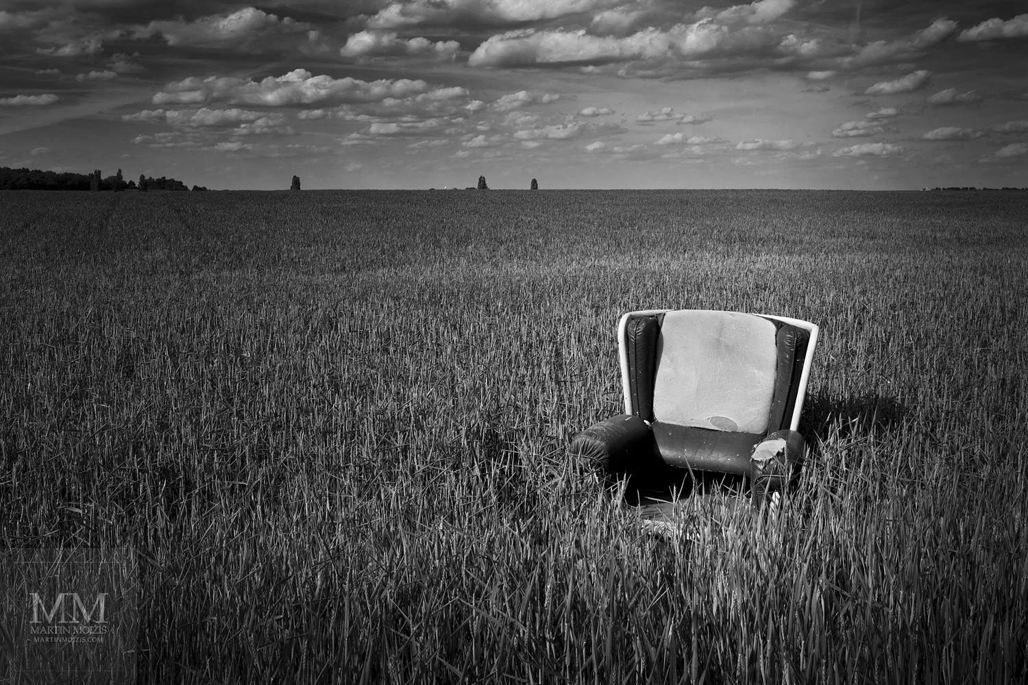 Křeslo v obilném poli. Umělecká černobílá fotografie Martina Mojžíše s názvem VÍTEJTE V MÉM DOMĚ IV.